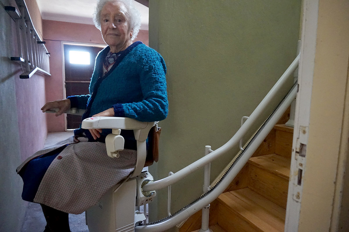 senhora idosa a usar um elevador de escadas Stannah